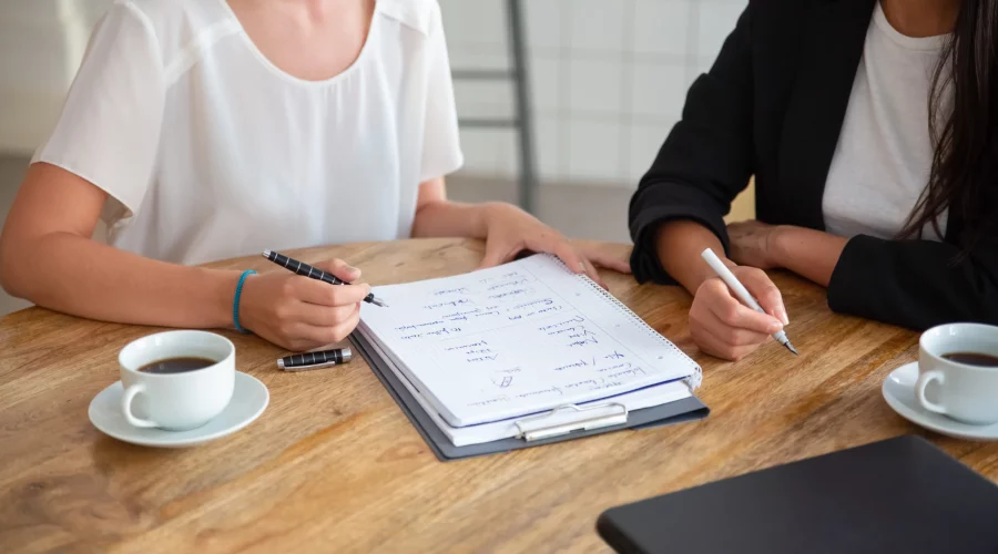 young-female-colleagues-meeting-discussing-business-plan-writing-strategy-scheme-paper-making-draft